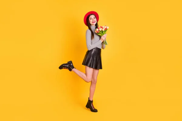 Foto de mulher muito jovem brilhante usar camisa listrada headwear segurando flores buquê isolado cor amarela fundo — Fotografia de Stock
