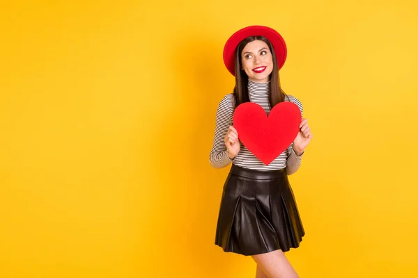 Foto de menina feliz sorriso olhar espaço vazio segurar vermelho papel coração romântico dia dos namorados isolado sobre cor amarela fundo — Fotografia de Stock