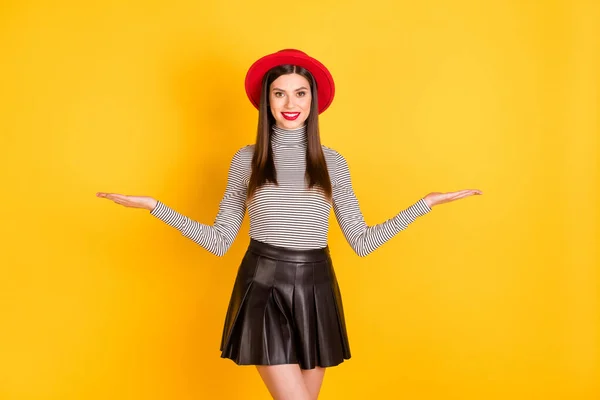 Foto de morena bonita senhora segurar as mãos espaço vazio presente objeto desgaste chapéu vermelho isolado no fundo cor amarela — Fotografia de Stock