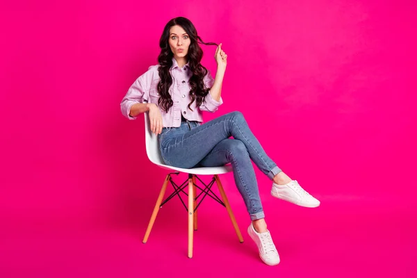 Full storlek foto av optimistisk brunett trevlig dam sitta blåsa kyss bära jacka jeans sneakers isolerad på rosa bakgrund — Stockfoto