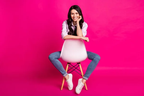 Full Size Foto von optimistischen Brünette schöne Dame sitzen tragen Jacke Jeans Turnschuhe isoliert auf rosa Hintergrund — Stockfoto