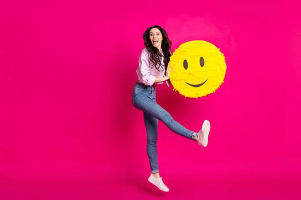 Foto de perfil em tamanho completo de otimista morena agradável senhora salto segurar pinata desgaste jaqueta jeans tênis isolado no fundo cor-de-rosa — Fotografia de Stock