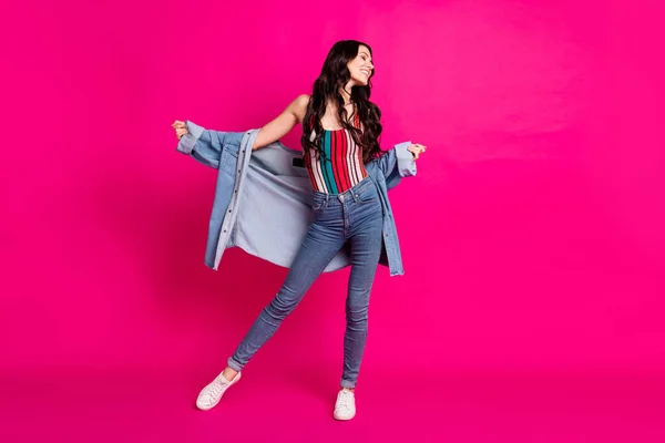 Full storlek foto av optimistisk brunett trevlig dam stå ser bära topp jacka jeans sneakers isolerade på rosa färg bakgrund — Stockfoto