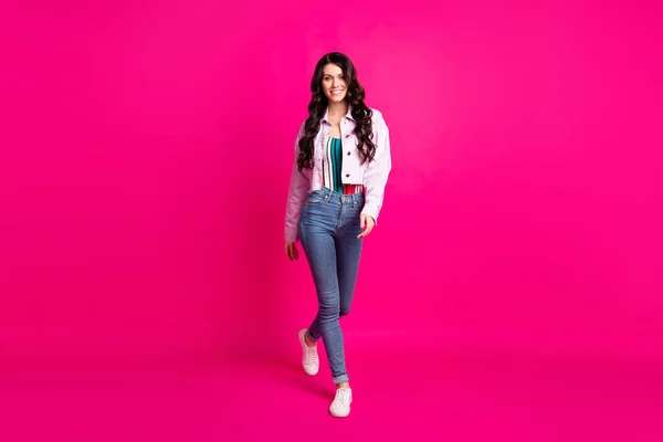 Volledige foto van vrij leuke jonge vrouw dragen jeans jas lopen geïsoleerde helder roze kleur achtergrond — Stockfoto