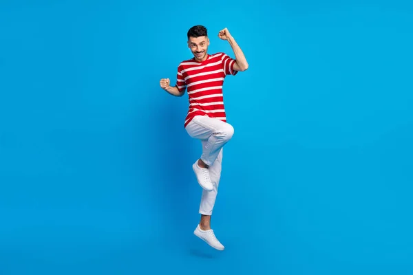 Full storlek foto av trevlig brunett hurra kille hoppa bära röd t-shirt byxor sneakers isolerad på levande blå färg bakgrund — Stockfoto