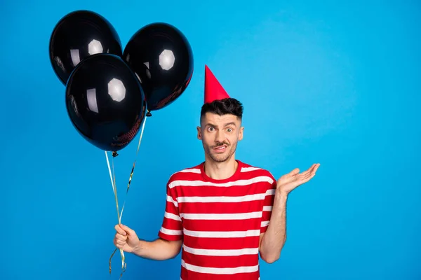 Foto de un joven infeliz irritado que celebra los globos de celebración de cumpleaños aislados en un fondo de color azul pastel —  Fotos de Stock