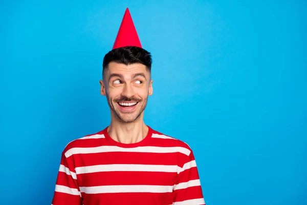 Foto de un joven alegre de ensueño que usa sombrero de cono de cumpleaños se ve espacio vacío aislado en el fondo de color azul pastel — Foto de Stock