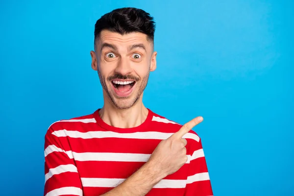 Foto de asombrado asombrado hombre alegre dedo índice vacío espacio noticias venta aislado sobre fondo de color azul —  Fotos de Stock