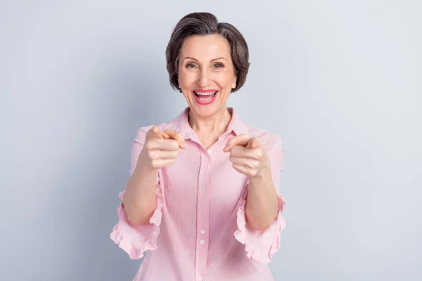 Porträt einer attraktiven, fröhlichen Frau, die mit zwei Zeigefingern auf Sie zeigt, isoliert über grauem Pastellfarbhintergrund — Stockfoto