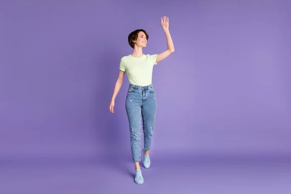 Full längd kroppsstorlek bild av attraktiv glad flicka promenader viftande hi hej isolerad över ljusa violett lila färg bakgrund — Stockfoto