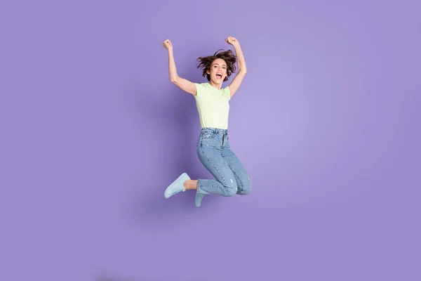 Повнометражний вигляд на тіло прекрасної худої веселої дівчини, що стрибає, розважаючись ізольовано на фіолетовому кольоровому фоні — стокове фото