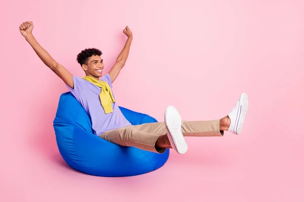 Foto de tamaño completo de joven feliz alegre sonriente hombre africano sentarse sillón levantar puños en la victoria aislado sobre fondo de color rosa — Foto de Stock