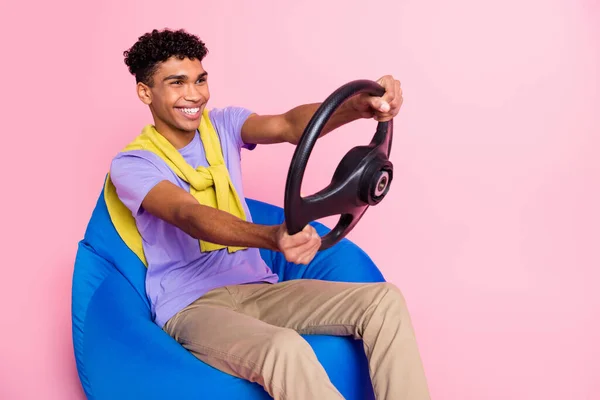 Foto de jovem feliz sorrindo positivo afro homem montando automóvel segurar volante isolado no fundo cor-de-rosa — Fotografia de Stock