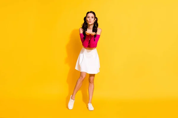 Vista completa del tamaño del cuerpo de la atractiva chica alegre y amorosa de pelo ondulado que envía un beso de aire aislado sobre un fondo de color amarillo brillante —  Fotos de Stock