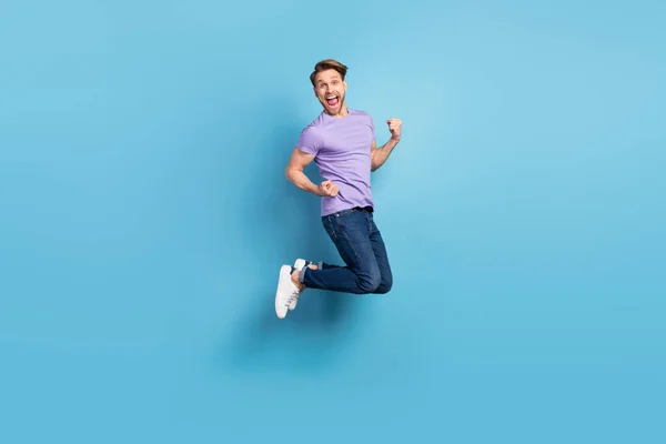 Фотографія повного тіла молодої людини, що стрибає з високим жестом, як переможець, ізольована на пастельному синьому фоні — стокове фото