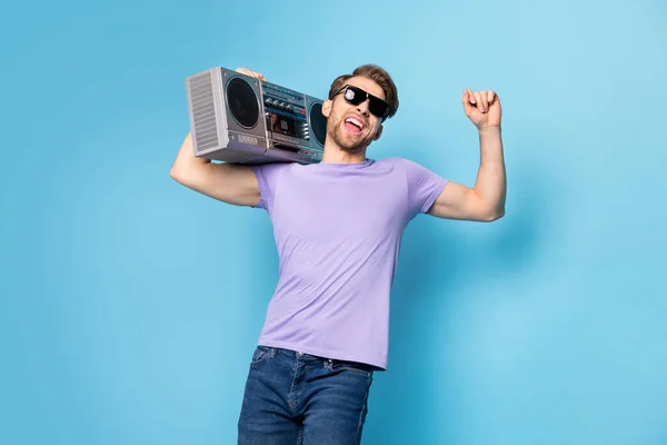 Foto portret van jonge man in zwart zonneglas houden boombox dansen geïsoleerd op pastel blauwe kleur achtergrond — Stockfoto