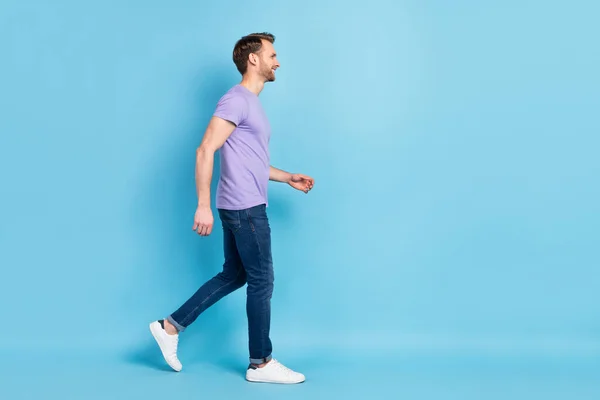 만족 해 하는 젊은 남자가 걸어 다니는 모습의 실물 사진은 푸른 색 배경에 고립된 빈 공간으로 보인다 — 스톡 사진