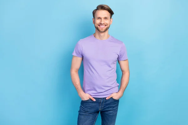 Photo portrait of young confident businessman in casual purple t-shirt smiling isolated on pastel blue color background — Stock Photo, Image