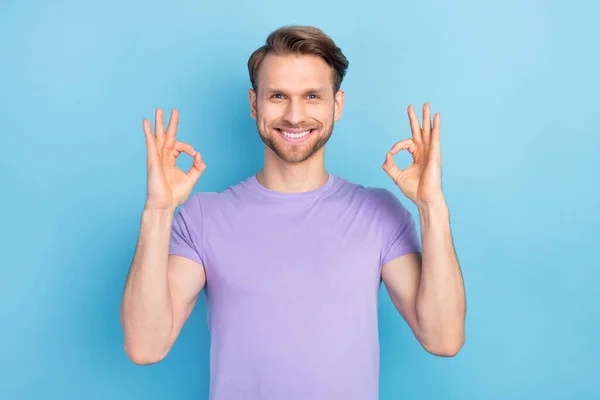 Φωτογραφία πορτρέτο του ανθρώπου δείχνει εντάξει χειρονομία με τα δύο χέρια χαμογελώντας σε μοβ ρούχα που απομονώνονται σε παστέλ μπλε χρώμα φόντο — Φωτογραφία Αρχείου
