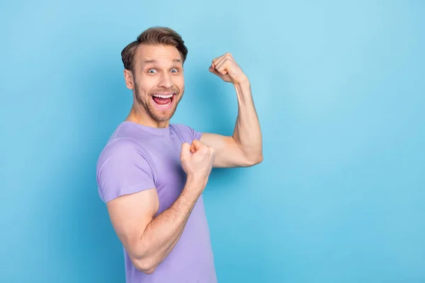 Φωτογραφία πορτρέτο του ανθρώπου δείχνει ισχυρό χέρι σε βιολετί t-shirt που απομονώνονται σε παστέλ μπλε φόντο χρώμα — Φωτογραφία Αρχείου