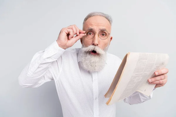 Photo de choc étonné étonné vieil homme porter des lunettes tenir journal isolé sur fond de couleur grise — Photo