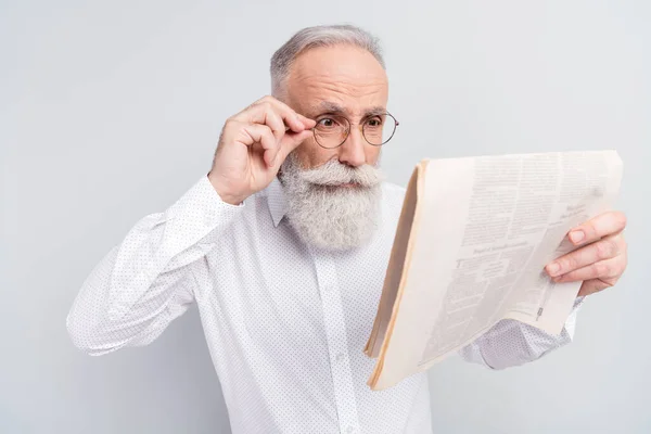 Photo d'homme âgé lunettes de contact à la main lire journal magazine nouvelles isolé sur fond de couleur grise — Photo
