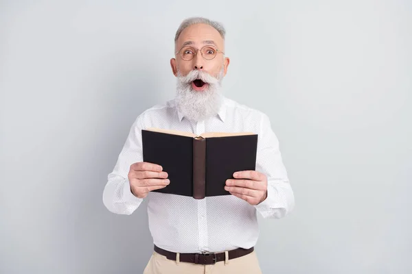 Foto de sorprendido sorprendido hombre viejo mantenga libro sorprendido gafas de desgaste de la trama aislado en fondo de color gris —  Fotos de Stock