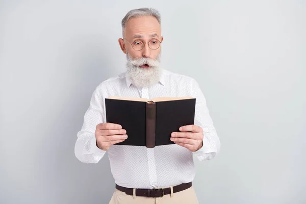 Foto de hombre anciano sorprendido sorprendido leer novela libro historia aislado sobre fondo de color gris — Foto de Stock