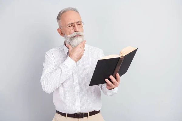 Foto de mirada de hombre viejo encantador de mente seria leer libro usar gafas aisladas sobre fondo de color gris —  Fotos de Stock