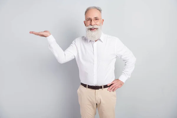 Foto av senior man glad positiv leende demonstrera hand produkt promo erbjudande isolerad över grå färg bakgrund — Stockfoto