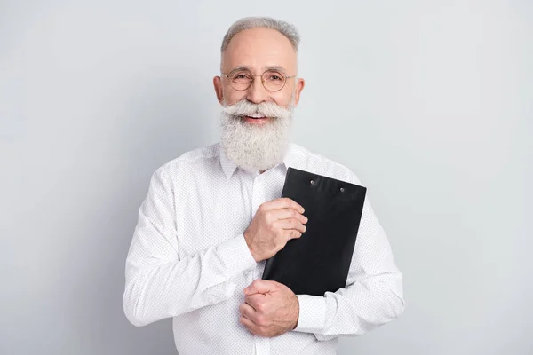 Foto av glad attraktiv charmig gammal man hålla Urklipp leende gott humör isolerad på grå färg bakgrund — Stockfoto