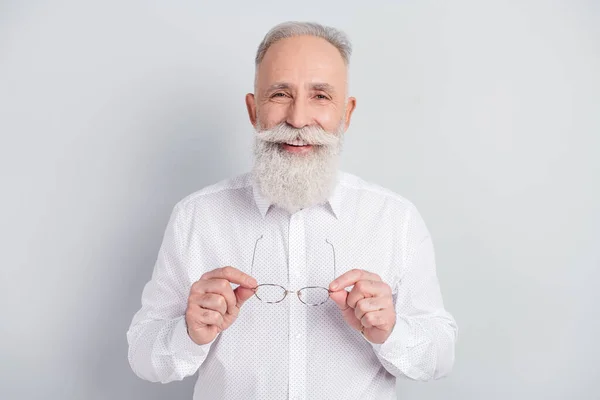 Foto di affascinante felice vecchio positivo tenere gli occhiali mani buon umore sorriso isolato su sfondo di colore grigio — Foto Stock