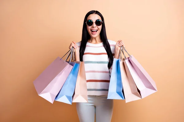 Foto van jong opgewonden meisje blij glimlach hold boodschappentassen verkoop geïsoleerd over beige kleur achtergrond — Stockfoto