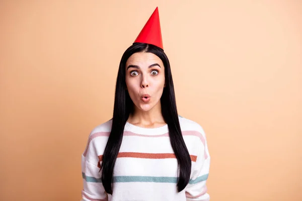 Foto von jungen erstaunt überrascht schockiert Mädchen mit roten Kegel auf dem Kopf feiern Geburtstag isoliert auf beige Hintergrund — Stockfoto