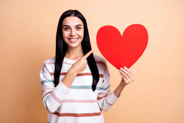 Foto de menina feliz sorriso indicar dedos grande papel vermelho coração anúncio promo aconselhar escolha isolada sobre fundo cor bege — Fotografia de Stock