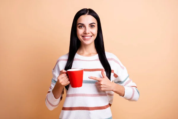 Foto de niña feliz sonrisa positiva indican taza de café anuncio promo aconsejar elegir aislado sobre fondo de color beige — Foto de Stock