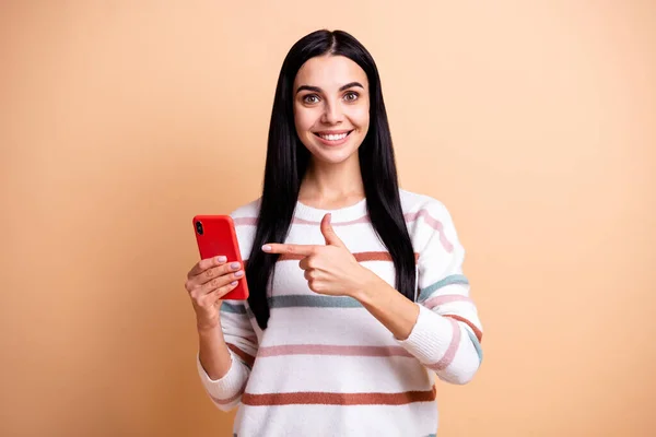 Foto di giovane felice felice allegro sorridente ragazza punta dito al telefono annuncio isolato su sfondo di colore beige — Foto Stock