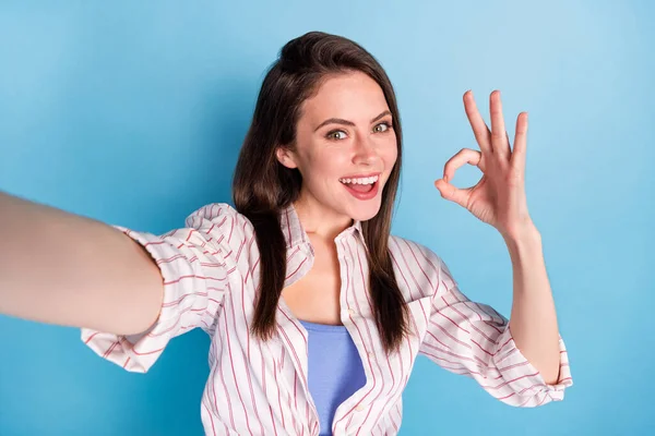 Photo of pretty cheerful girl take selfie fingers show okey symbol beaming smile isolated on blue color background — ストック写真