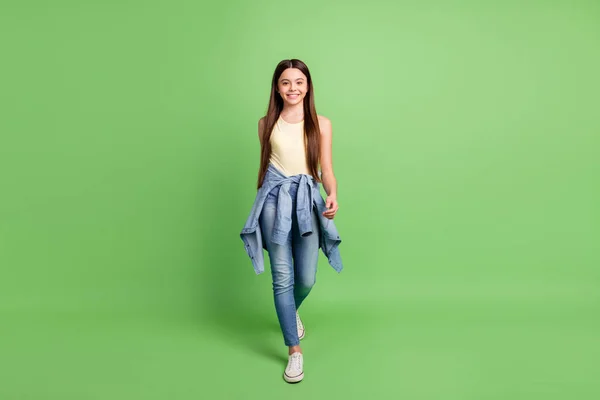 긍정적 인 미소를 짓고 있는 젊고 흥분 한 소녀의 전체 길 이 사진 녹색 배경 위에서 고립된 걸음걸이를 하고 있다 — 스톡 사진