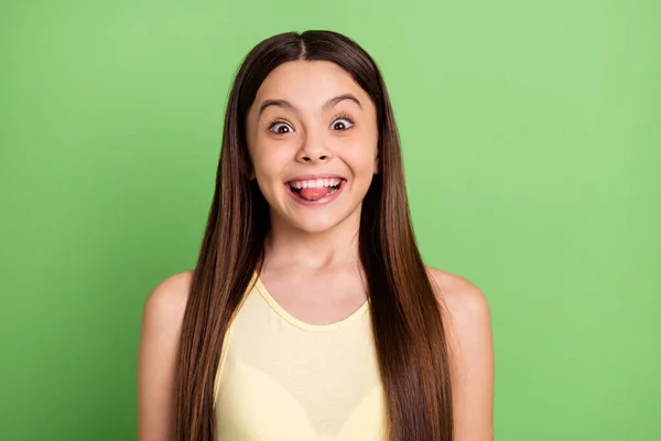 Foto de la sonrisa dentada alumna loca positiva morder lengua mirada cámara aislada sobre fondo de color verde — Foto de Stock