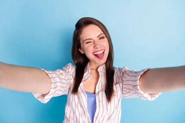 Photo of charming cheerful lady make selfie eye wink show tongue out isolated on blue color background — Stock Image Photo of charming cheerful lady make selfie eye wink show tongue out isolated on blue color background Stock Picture