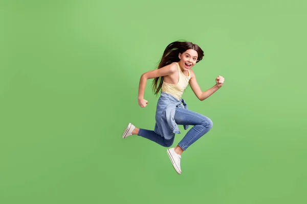 全身上下都是一个充满活力、快乐的女孩在明亮的绿色背景下独自奔跑的景象 — 图库照片
