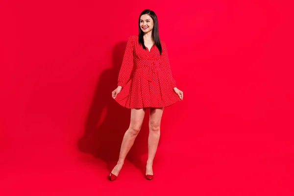 Teljes méretű fotó édes barna hölgy állni néz üres tér kopás piros ruha cipő elszigetelt élénk szín háttér — Stock Fotó