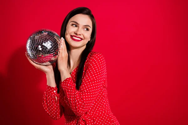 Foto de la señora morena fresca mantenga disco bola mirada espacio vacío desgaste vestido rojo aislado sobre fondo de color vivo —  Fotos de Stock