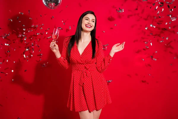 Foto de lujo impresionado morena dama mantenga el vidrio mirada espacio vacío desgaste vestido rojo aislado sobre fondo de color vivo —  Fotos de Stock