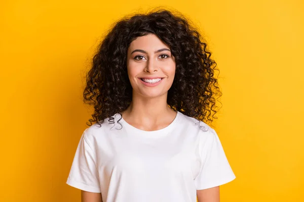 Foto retrato de la alegre morena rizada con camiseta blanca sonriendo aislada sobre fondo de color amarillo brillante —  Fotos de Stock