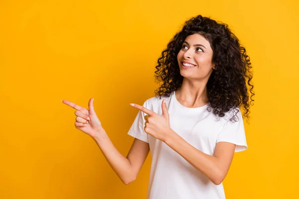 Foto retrato de la morena rizada mostrando buscando espacio vacío promoviendo aislado sobre fondo de color amarillo brillante —  Fotos de Stock