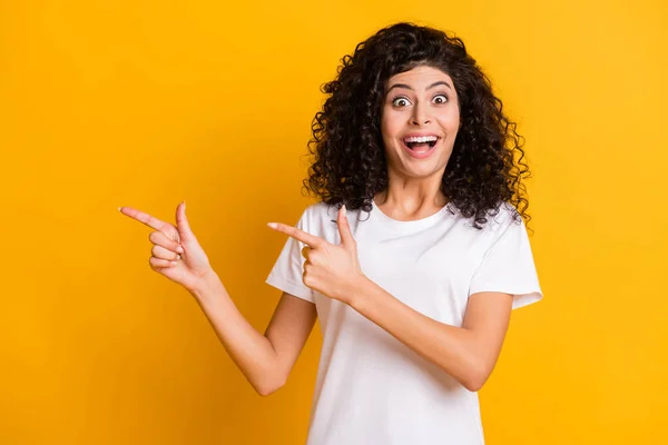 Foto retrato de chica sorprendida mostrando los dedos copyspace mirando sonriendo aislado sobre fondo de color amarillo vivo — Foto de Stock