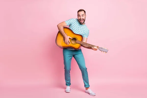 Longitud completa tamaño del cuerpo vista de chico alegre agradable tocando la guitarra de cuerda país estilo diferente divertirse aislado sobre fondo de color rosa —  Fotos de Stock