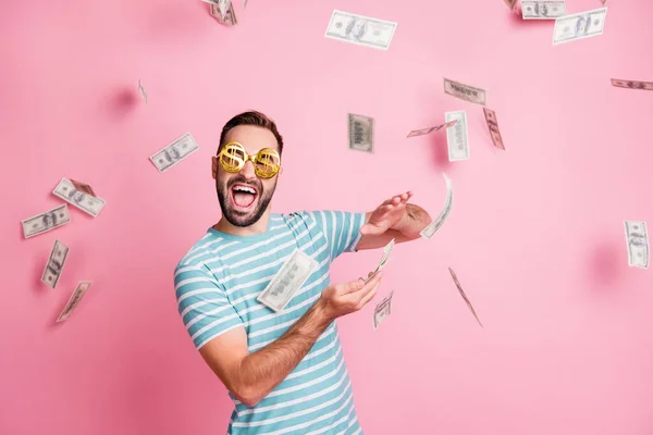 Retrato de buen chico alegre funky usar especificaciones de dólar lanzando moneda nosotros 100 cientos presupuesto aislado sobre fondo de color pastel rosa — Foto de Stock